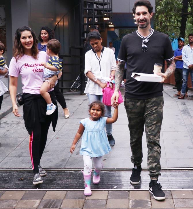 Sunny Leone was spotted with husband Daniel Weber and kids in Juhu, Mumbai. The actress looked pretty powder pink slogan tee, paired with black jeggings and glittery slip-on for the outing. Daniel sported a basic black t-shirt, paired with camouflage pants and black sneakers. All pictures/Yogen Shah