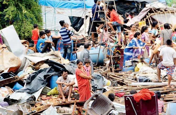 Local residents search for salvageable belongings amidst the debris of their homes crushed under a wall that collapsed on Monday night