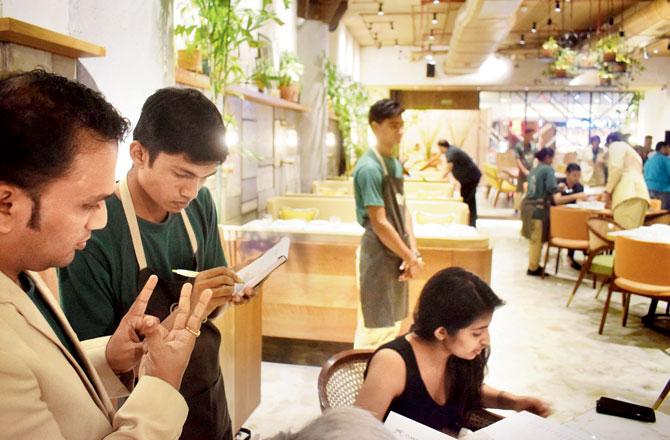 A waiter takes down the order while another staffer helps the customer with the sign language. Pics/AsHish Raje