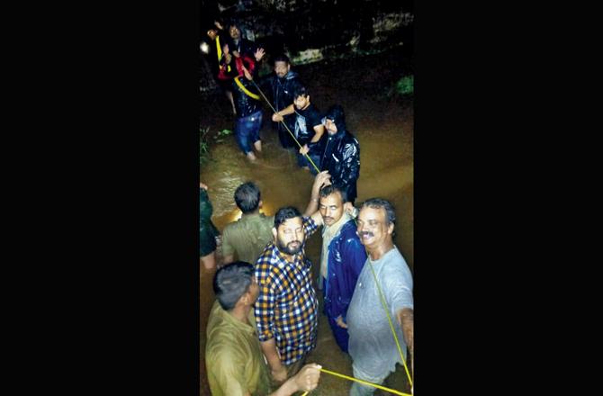 Passengers use ropes to negotiate the water-logged tracks