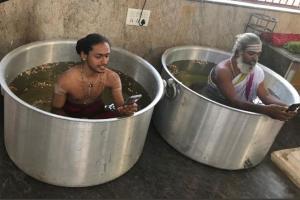 Priests sit in vessels filled with water to pray for better monsoon