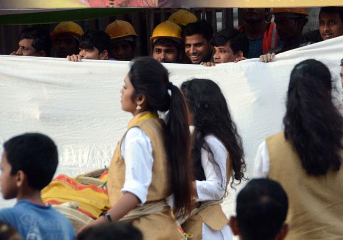 Under construction worker watching the girls playing Nashik Dhol during the Mumbai Bodybuilding competition 'Mumbai Shree 2019', organised by Maharashtra Navnirman Sena (MNS) at Vithaldas Nagar, Khar in Mumbai on Sunday. 