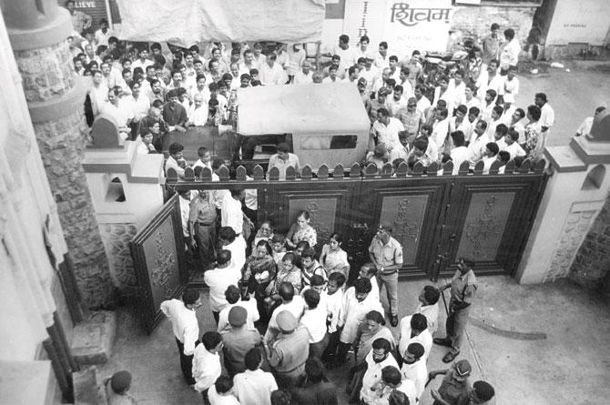 People gather outside a court in Mumbai to see an accused being taken away.