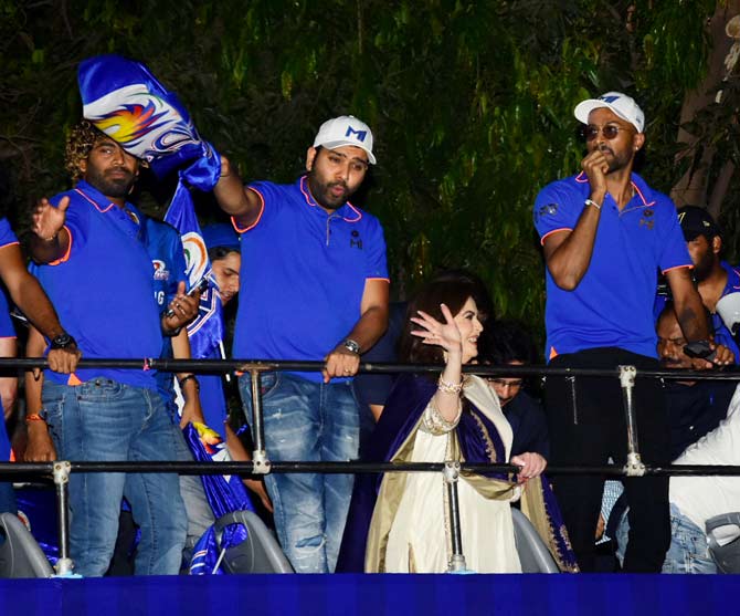 Mumbai Indians skipper Rohit Sharma proudly waves the flag and interacts with the crowd as Hardik Pandya and Lasith Malinga look on