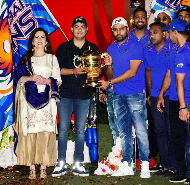 Akash Ambani and Rohit Sharma hold the IPL 2019 trophy, while Nita Ambani smiles away at Antilia