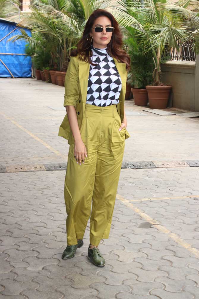 Esha Gupta opted for a formal neon pantsuit which she teamed up with a multi-coloured tee and retro sunglasses. The actress takes her style quotient a notch higher by donning classy yet quirky outfits in her various appearances. And this time, she is no different.