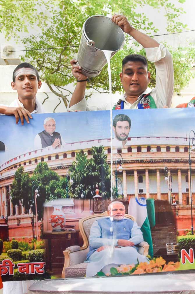 NDA supporters pour milk over a photo of Prime Minister Narendra Modi after their victory at Lok Sabha polls, in Patna, Friday, May 24, 2019