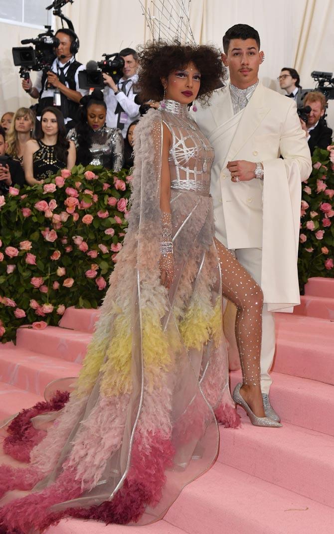 Priyanka Chopra and Nick Jonas made their grand return to the 2019 Met Gala as a married couple and it's safe to say that the two totally slayed their looks on the pink carpet. The newlyweds arrived hand-in-hand and posed for the cameras. The two brought their fashion A-game as they wore over-the-top ensembles for the mega event. Priyanka looked absolutely stunning in a Dior Haute Couture silver gown with colourful and vibrant feathered ruffles coupled with a matching cape. Nick looked dapper in a white Dior Men tux and sparkly silver Christian Louboutin shoes.