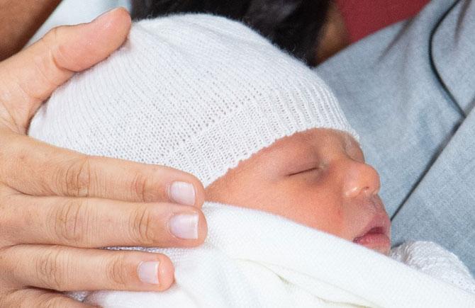 With a bright smile on his face, Prince Harry held little Archie, who was wrapped in a white blanket, close to his chest. 