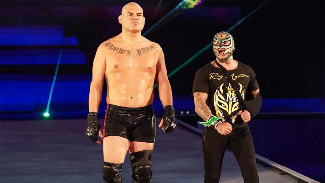 Former UFC champion Cain Velasquez, who beat Brock Lesnar nine years ago, makes his way to the ring alongside Rey Mysterio