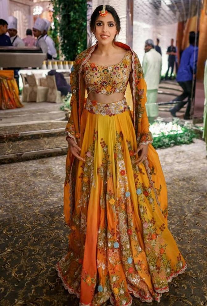 In June 2019, designer Anamika Khanna shared a beautiful picture of Akash Ambani's wife Shloka Mehta in a pretty lehenga choli. Shloka, who looked like an epitome of grace and beauty, donned a mustard yellow and orange lehenga choli which had a thick border around her waist. The blouse was embroidered with floral motifs while her dupatta was equally pretty. Shloka completed her look with a flower maang-teeka, minimal make-up, and nude lipstick. She complimented her ethnic look by tying her hair in a neat bun