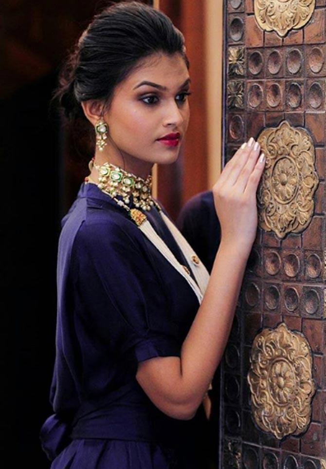 Once again, it is her jewellery that accentuates her look on this dark blue gown. With heavy, statement earrings and a neckpiece, the red lipstick adds to her look. 
