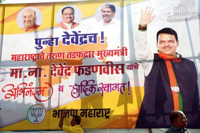 BJP workers put up a poster of Devendra Fadnavis after his swearing-in as chief minister early Saturday morning