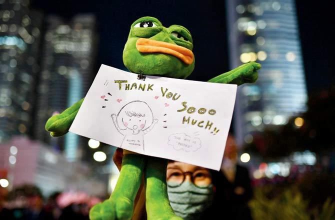 People hold up lights from their phones; a participant holds up Pepe the Frog, a character used as a symbol of their struggle, at  a gathering of thanks after Donald Trump signed the bill. Pics/AFP