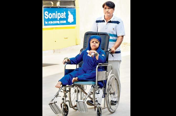 A volunteer takes a differently abled person to a polling booth in Sonepat on Monday. Pic/PTI