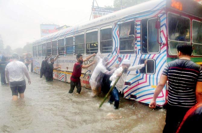 Helpful citizens try and get a stalled bus back on the move on a waterlogged road at SV Road in Andheri. Pic/Sayyed Sameer Abedi