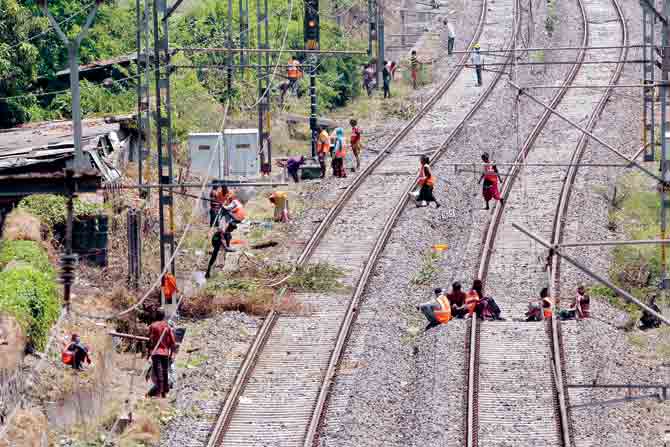 Railway workers clear dirt and overgrowth near tracks on Wednesday. PIC/SAYYED SAMEER ABEDI
