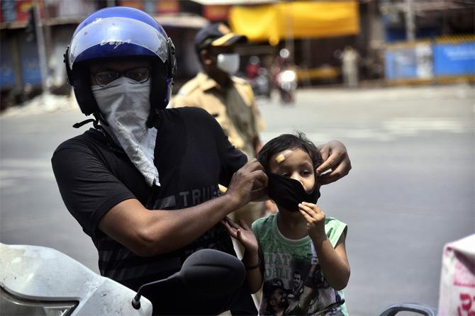 In photo: Safety first! A man was caught in a candid moment while he was trying to put a face mask on his son's face at Dharavi.