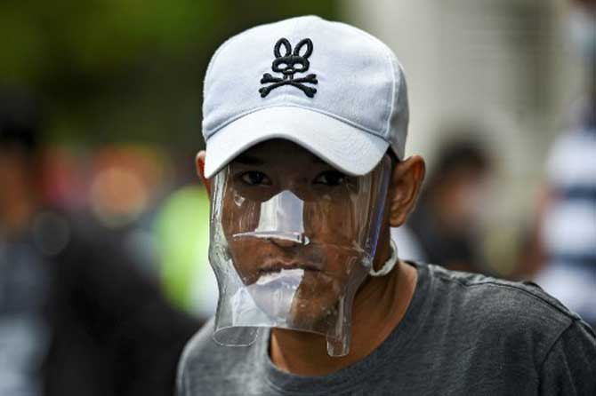 A Venezuelan migrant wears a plastic water bottle with a cutout to cover his face as he waits to be checked by health workers to rule out the novel coronavirus as part of his repatriation process in Cali, Colombia.