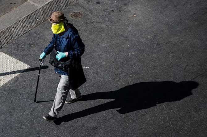 A woman wearing a home made protective mask walks in a street in Paris, France.