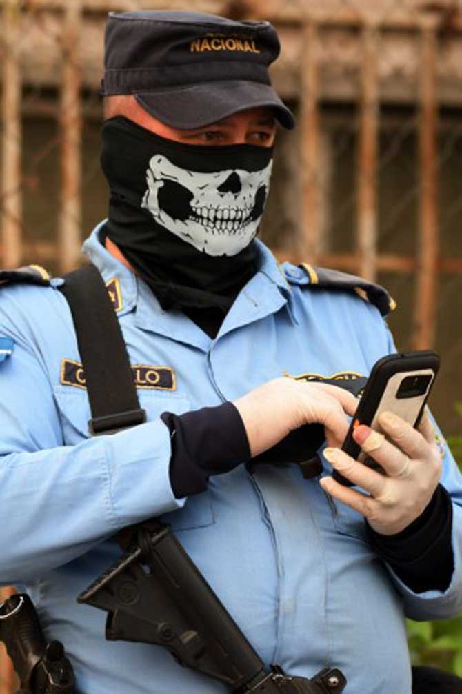 A policeman wears gloves and a face mask depicting a skull as a preventive measure against the spread of coronavirus as he stands guard in a street of Tegucigalpa in Honduras.