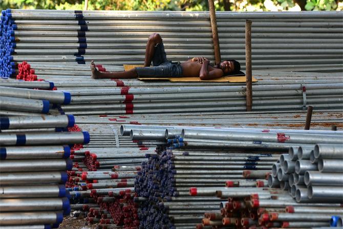 In photo: A labourer snapped while taking nap on iron rods at an industrial area in Mumbai's Cotton Green area.