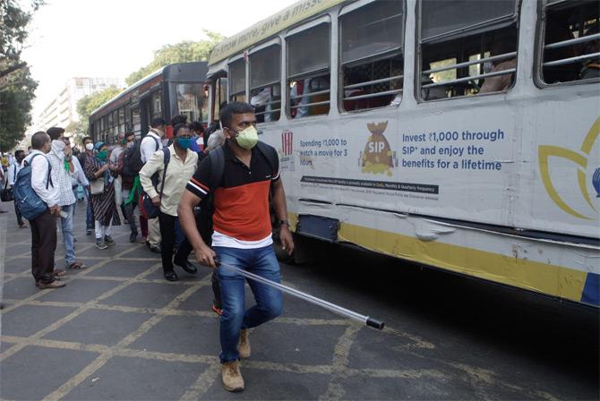 In photo: A police personnel controls the crowd trying to board buses in Mumbai