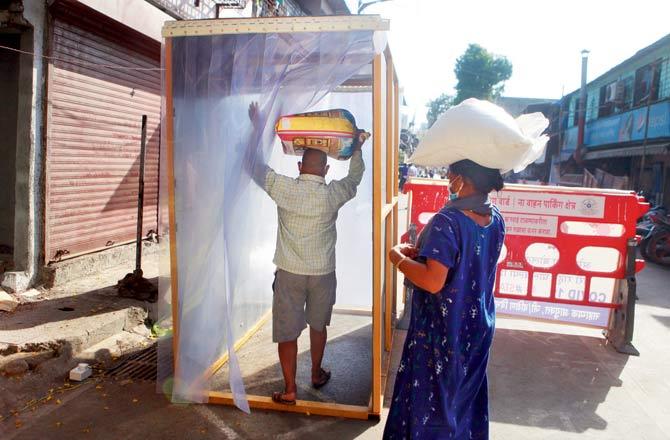 Locals sanitise themselves by entering a disinfection tunnel at Jijamata Nagar in Worli