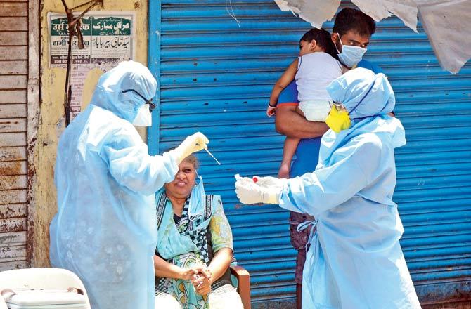 Residents of Sewri slums being screened and tested after a suspected contact with a COVID-19 positive patient in the area on Wednesday. Pic/Suresh Karkera
