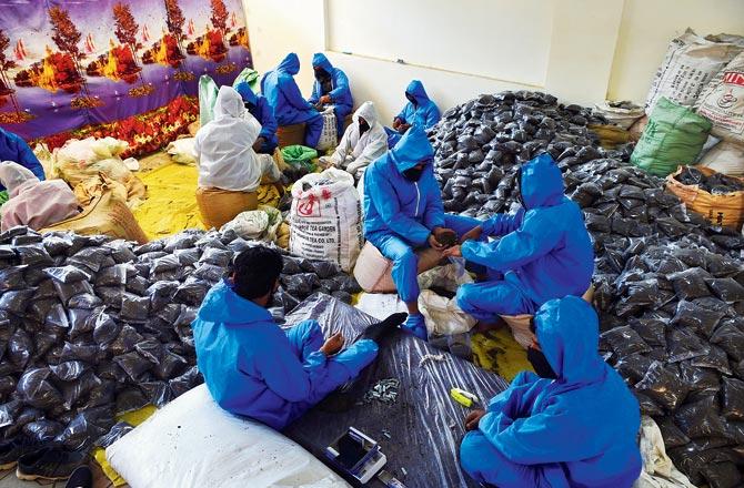 Workers wearing protective suits prepare food packets to distribute among needy people arranged by the district administration in Srinagar, on Tuesday Pic/PTI