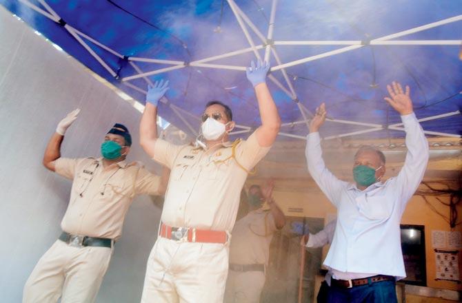  Dharavi police get sprayed with disinfectant before entering Dharavi police station on Sunday. Pic/Suresh Karkera