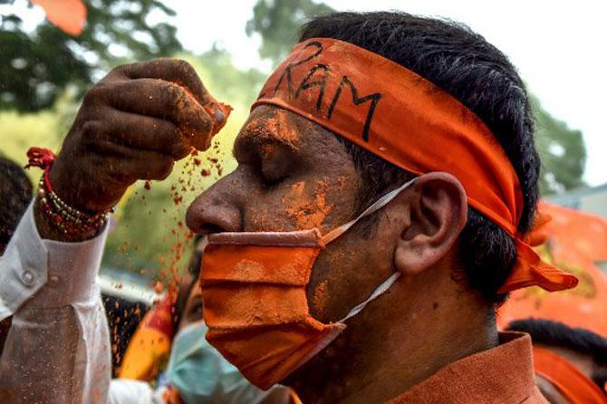 BJP activists and supporters apply saffron colours on their face as they celebrate minutes before the groundbreaking ceremony.