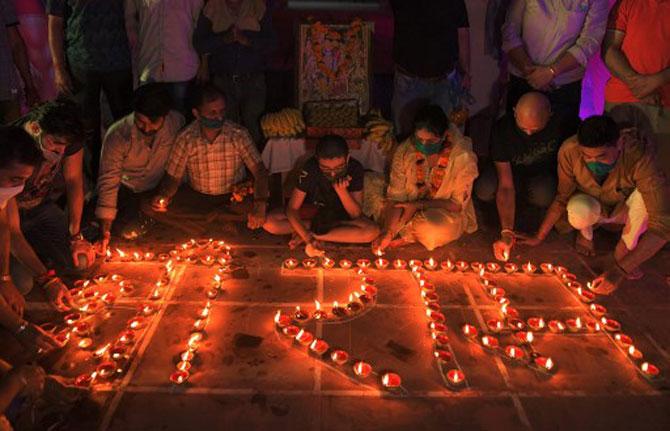 Hindu devotees light oil lamps forming the words 