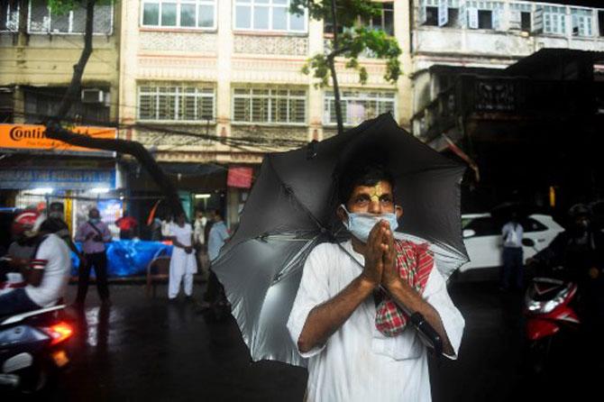 In photo: A devotee, armed with an umbrella and face mask, offers prayers in front of the idols of Lord Ram during a special prayer, in Kolkata.