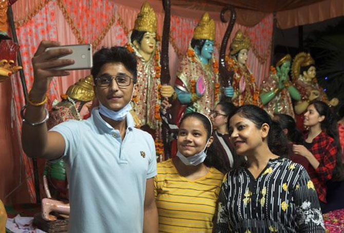 A group of youngsters poses for a selfie in front of Lord Ram idols.
