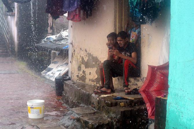 Bus services of the Brihanmumbai Electric Supply and Transport (BEST), the city civic body's transport wing, were also affected due to inundation in several areas, leading them to divert more than 30 routes.
In picture: Two boys, sitting on the doorstep of their house, watch rains in Saath Rasta.