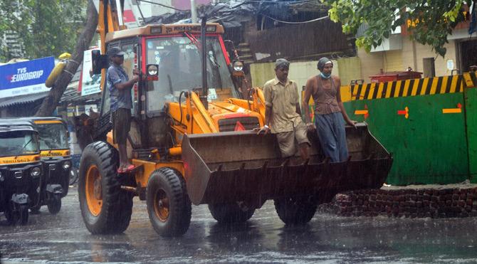In picture: Two men enjoy a joyride on a bulldozer amid the heavy rains.