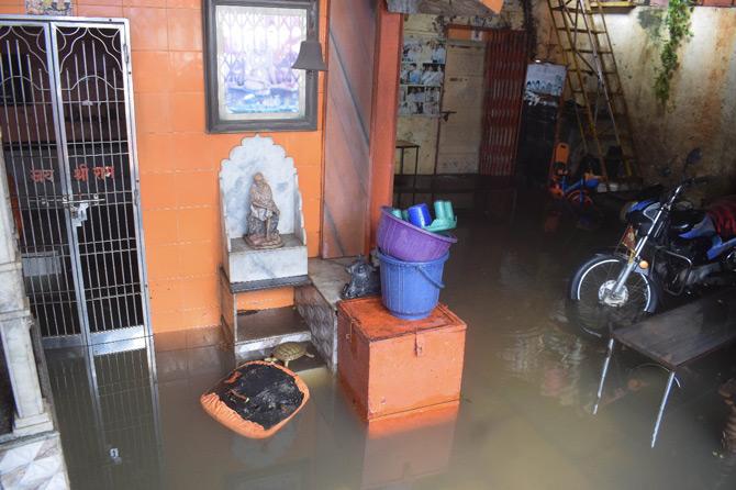 In picture: A makeshift temple stands strong as vehicles are submerged in floodwater in Kurla.