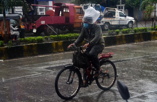 In picture: A man covered his head with a plastic bag to protect himself from the rain while riding a bicycle. 