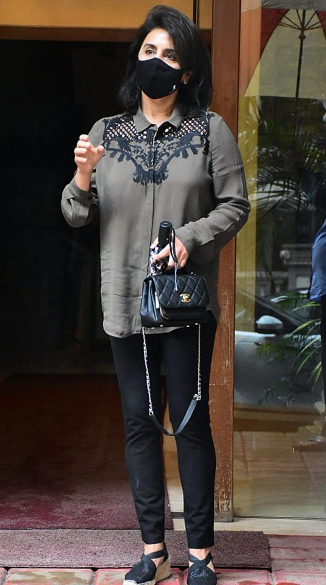 Neetu Kapoor opted for a casual attire for her outing. She donned a grey shirt dress and black pants. She looked elegant in her attire. Giving her a good company was her black shoes, handbag and a matching mask. She also carried a blue umbrella to keep herself protected from the rains.