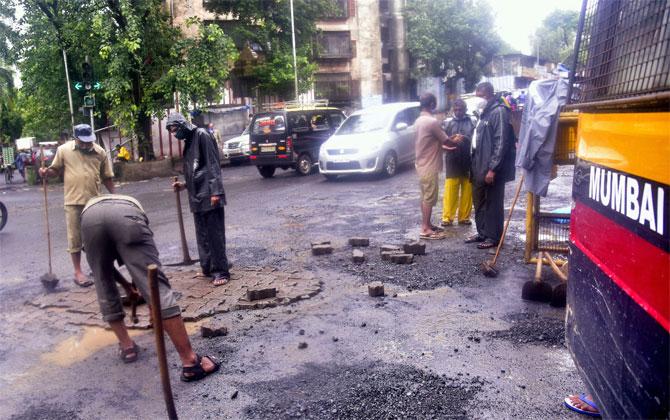 In photo: BMC workers filling potholes at Sion.