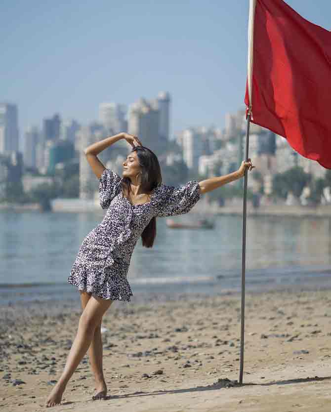 The beauty titleholder poses graciously in a printed dress at a beach for a photo shoot.