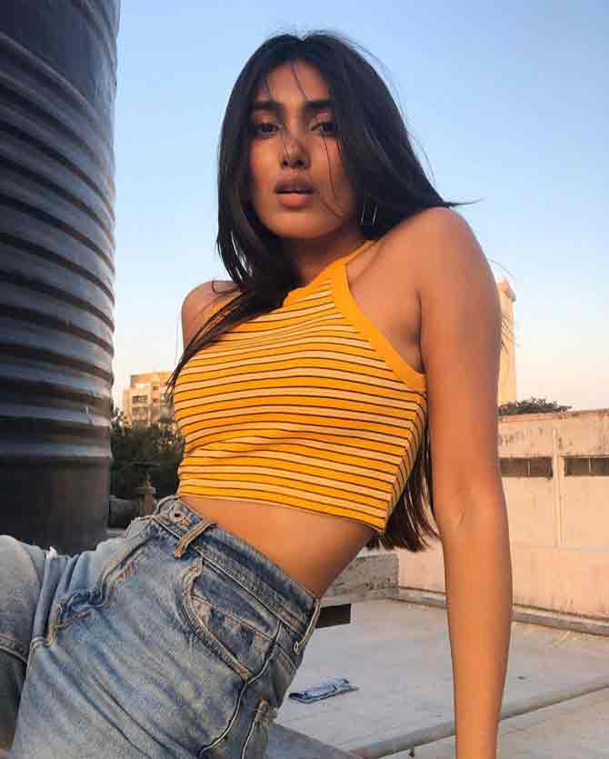 She strikes a stylish pose in a halter neck crop top and a pair of blue denim pants