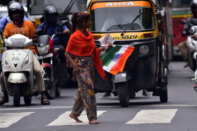 In photo: A young girl selling National flags on a busy street in Santacruz.