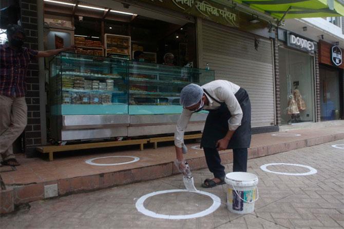 In photo: A shopkeeper draws a circle outside his shop in Dadar to ensure that customers maintain social distancing.