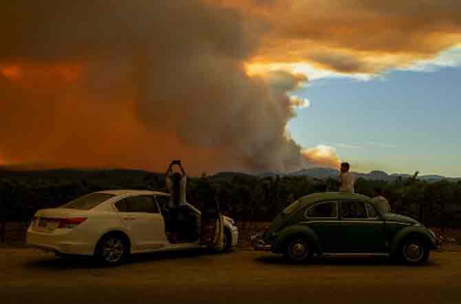 Thousands of firefighters struggled to put out the historic wildfires in California, with potentially dangerous lighting storms proving milder than expected and temperatures easing.
In picture: People watch the Walbridge fire, part of the larger LNU Lightning Complex fire, from a vineyard in Healdsburg, California.