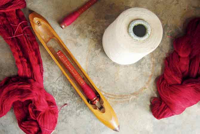 (Above) Yarn and shuttle for handloom weaving; (Bottom) A woman weaver works on handloom yarn at master weaver Vishram Valji Vankar’s home at Bhujodi, Kutch. PIC COURTESY/ARTISANS’