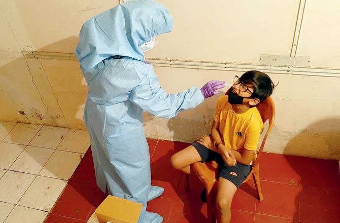 A child gets tested for COVID-19 at an antigen testing camp in Malad