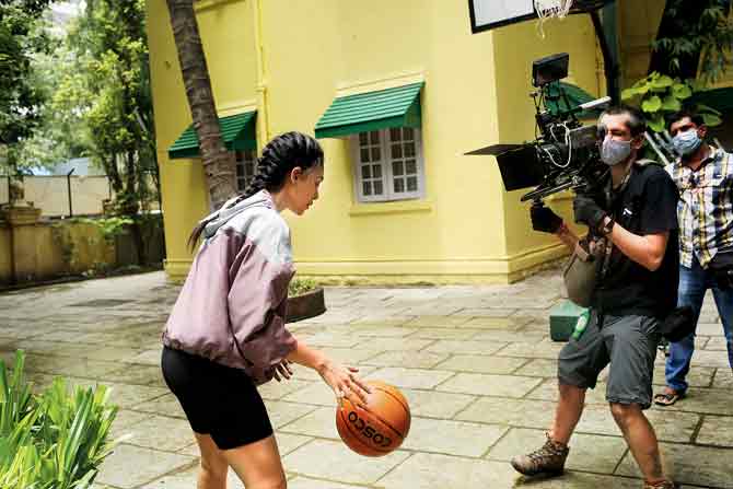 The director of photography, wearing a mask and gloves, captures Dhulipala in action