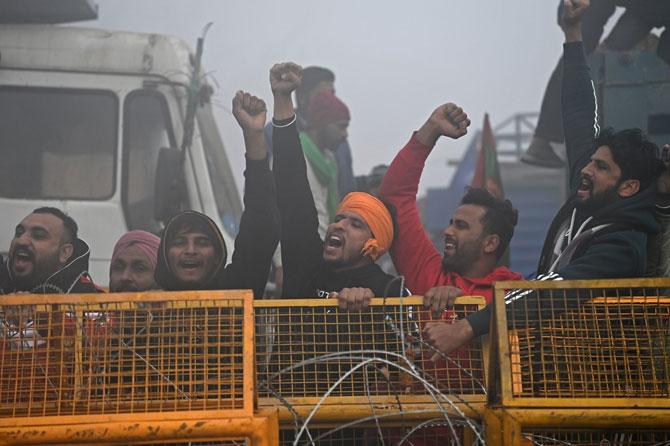 Farmers shout slogans next to a police barricade amid foggy condition during a nationwide general strike to protest against the recent new farm laws at the Delhi-Haryana state border in Singhu on December 8, 2020. Photo: AFP